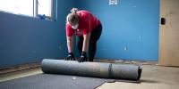 A person rolling up a carpet.