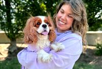 Woman wearing a purple shirt holding a dog