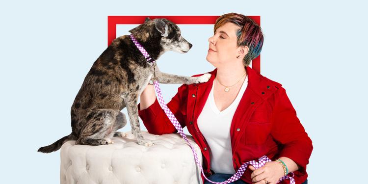 Woman in red jacket petting dog with a purple leash