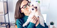 Una mujer sostiene de cerca a su perro pequeño con los ojos llorosos