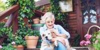 owner sitting on front porch petting dog with ivy plants