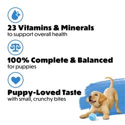 A yellow lab puppy bows down playfully with a blue tennis ball on a white and blue background in the bottom right corner. Next to the puppy is bullet-pointed text that reads "23 vitamins and minerals to support overall health, 100% complete and balanced for puppies, puppy-loved taste with small, crunchy bites."