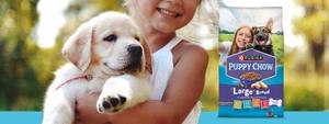 young girl holding a puppy, next to the puppy chow package