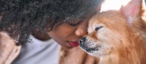 A puppy and its owner resting their heads together with their eyes closed
