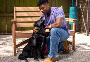 Man kneeling on ground with black dog