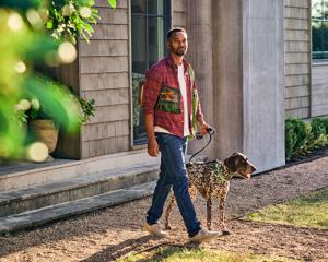 A man walks his dog with him to recycle an empty bag of Purina Pro Plan dry dog food.