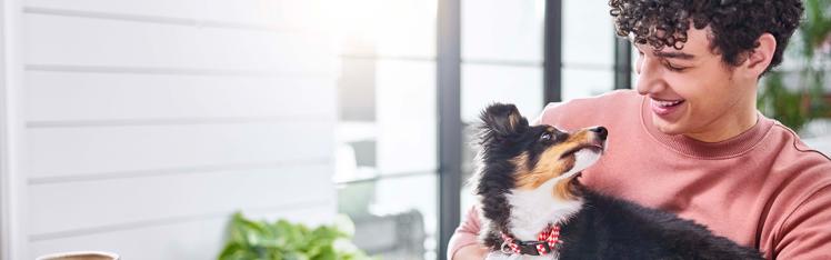 A human smiling down at their puppy looking back up at them