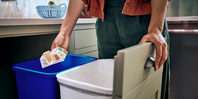 A person recycles a Fancy Feast wet cat food container.